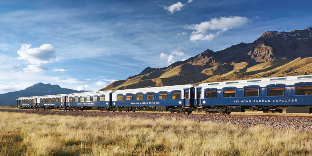The Belmond Andean Explorer train traveling through the Peruvian Andes, with snow-capped mountains in the background
