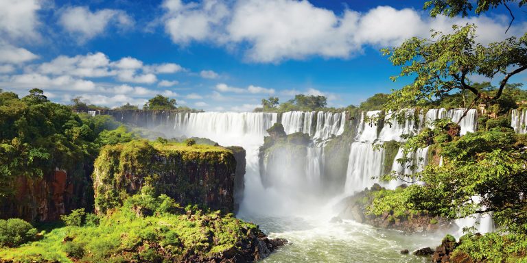 A view of Iguazu Falls, with multiple waterfalls cascading into a river.