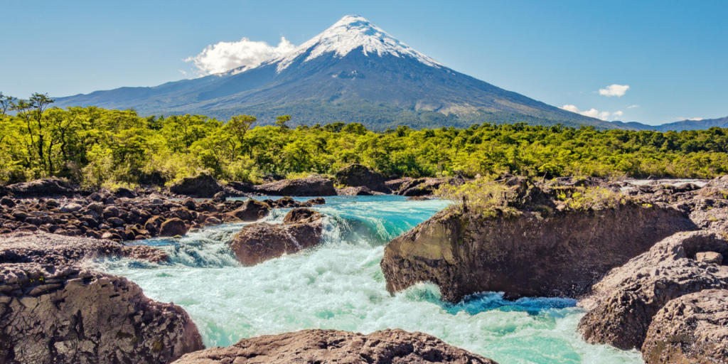 A breathtaking view of Petrohué Falls in Chile, with the snow-capped Osorno Volcano in the background.