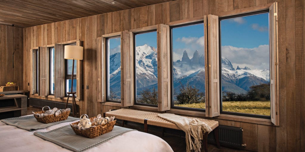 A cosy bedroom in Awasi Patagonia hotel with large windows overlooking the snow-capped Torres del Paine mountains.