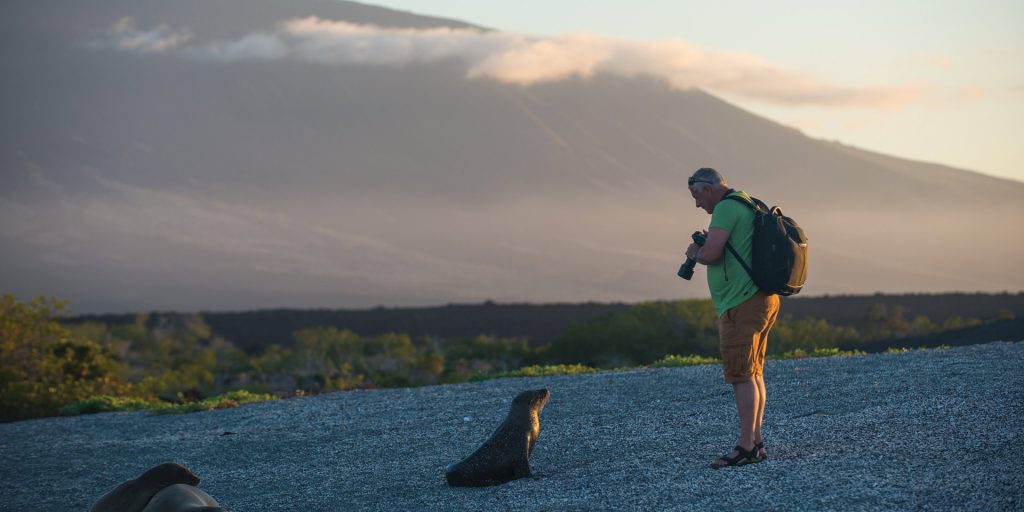 Man with a seal by the beach in Galapagos