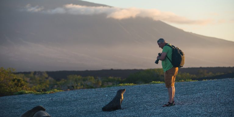 Man with a seal by the beach in Galapagos