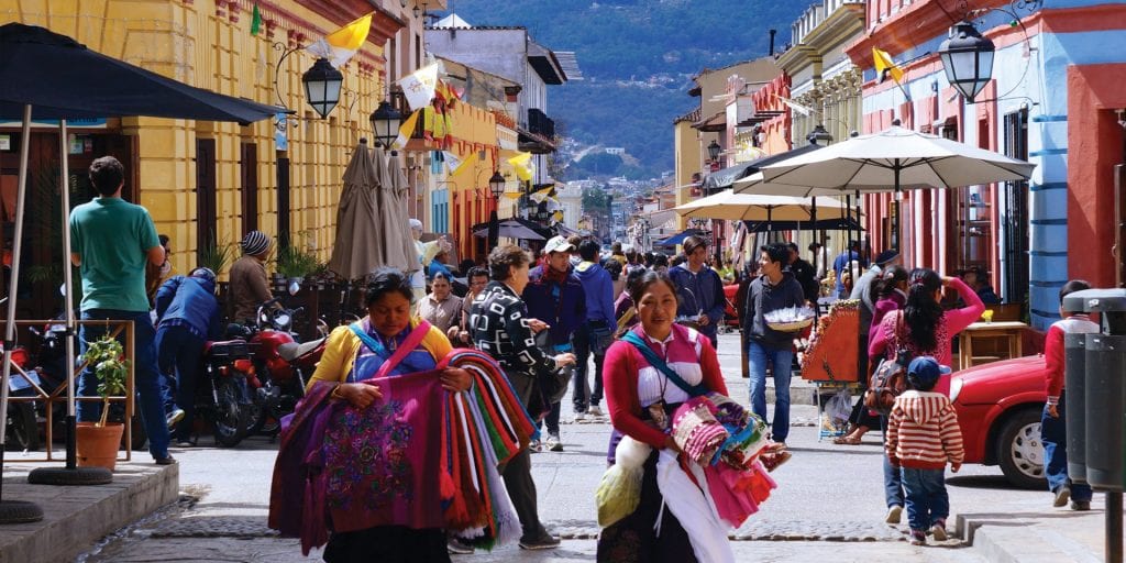 Lively street scene in San Cristobal de las Casas, Mexico, featuring local people and colorful architecture, ideal for a "Discover Mexico" tour introduction.