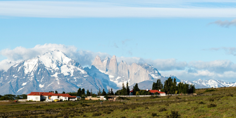 A scenic view of Estancia Cerro Guido, a luxury hotel in Torres del Paine National Park, Chile. The hotel is surrounded by beautiful mountains and grasslands.