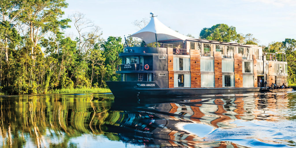 A luxurious cruise ship sailing down a river in the Amazon rainforest.