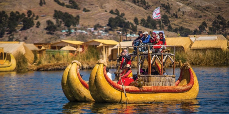 A traditional reed boat carrying tourists near the floating islands made of reeds on Lake Titicaca