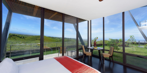 A spacious hotel room with floor-to-ceiling windows offering panoramic views of the Galapagos landscape.