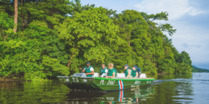 A guided boat tour in Tortuguero, Costa Rica, with lush green vegetation on the banks.