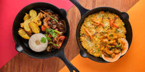 Two sizzling cast-iron pans filled with Peruvian dishes: Lomo Saltado, a stir-fry with beef, vegetables, and soy sauce, and Arroz Chaufa, a Chinese-Peruvian fried rice with seafood and vegetables.