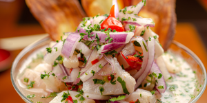 A bowl of ceviche with fresh white fish, red onion, chili peppers, and cilantro.