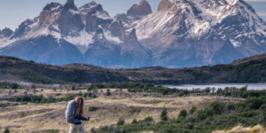 Person trekking with mountains and a lake in the distance.