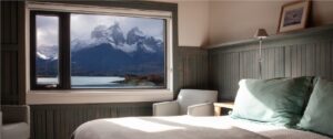 Interior design of a room at Explora Torres del Paine showcasing natural wood paneling, comfortable armchairs, and a scenic window view.
