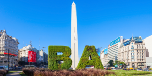 The Obelisk of Buenos Aires rises above the city skyline, flanked by green "BA" letters.