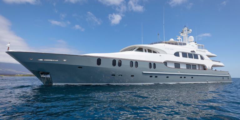 Aqua Mare yacht sailing on the blue waters of the Galapagos, with a clear sky backdrop.
