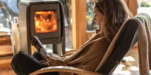 This inviting image showcases the interior of a yurt at Patagonia Camp, featuring a wood-burning stove and a woman enjoying the serene ambience.