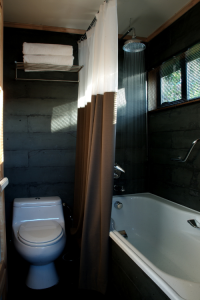 A small, modern bathroom featuring a white bathtub, a toilet, a shower curtain, and a showerhead.