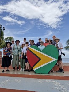 Group of travelers at the heart-shaped Guyana flag monument.